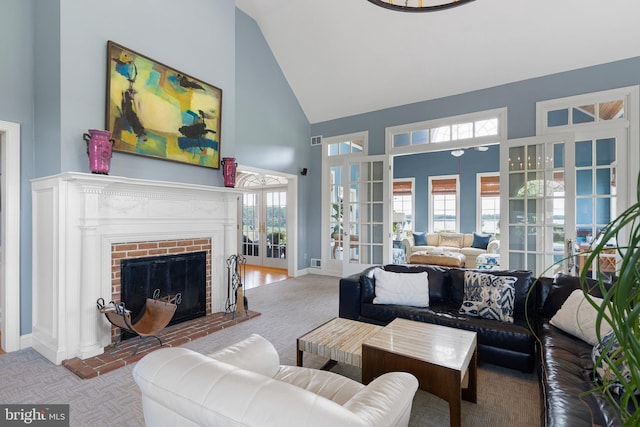 carpeted living room with a fireplace, high vaulted ceiling, and french doors