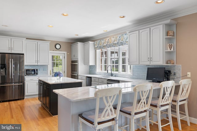 kitchen featuring light stone countertops, appliances with stainless steel finishes, sink, a center island, and white cabinetry