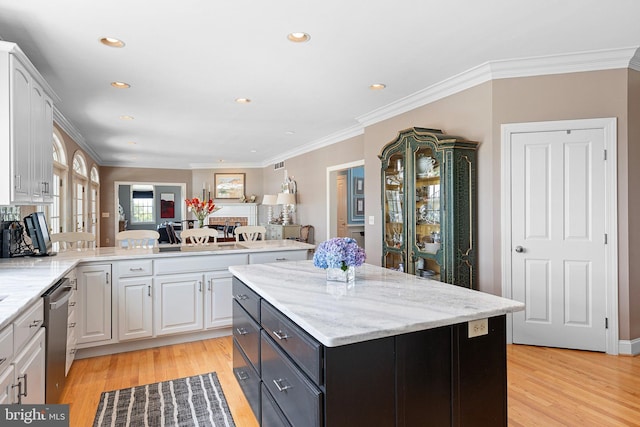 kitchen featuring white cabinets, a center island, stainless steel dishwasher, and ornamental molding