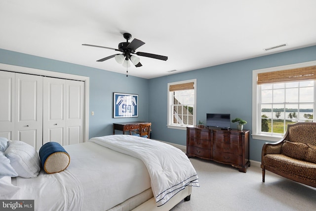 bedroom with multiple windows, light carpet, a closet, and ceiling fan