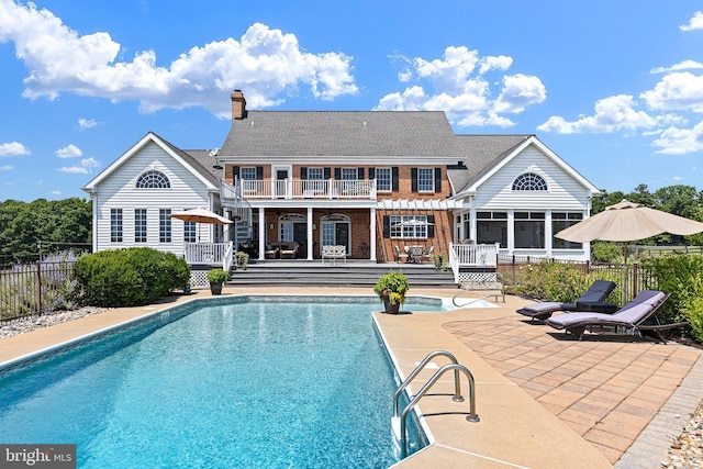 back of property featuring a patio area, a swimming pool side deck, a balcony, and a sunroom