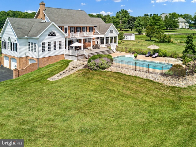 back of property with a pool side deck and a lawn