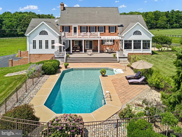 back of house with a lawn, a sunroom, a swimming pool side deck, and a patio