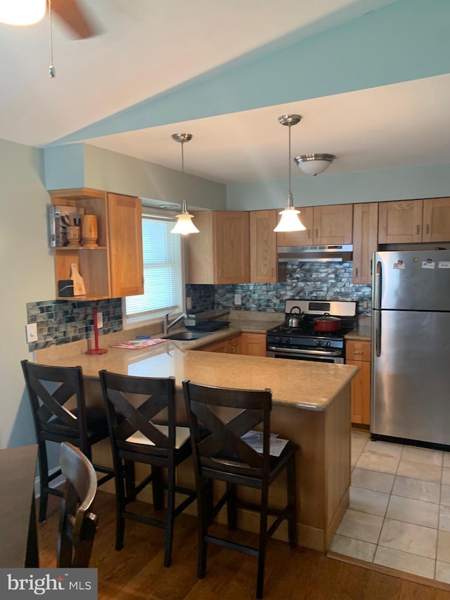 kitchen with kitchen peninsula, hanging light fixtures, stainless steel appliances, a breakfast bar, and sink