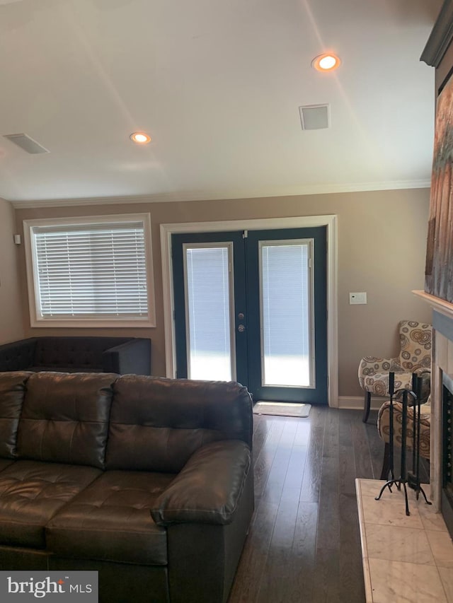 living room with ornamental molding, dark wood-type flooring, french doors, and a tile fireplace