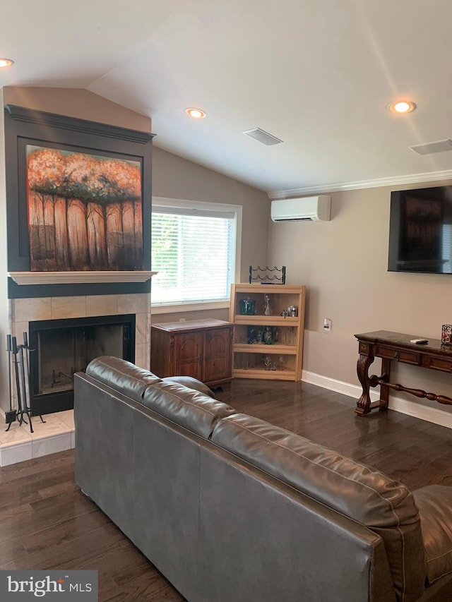 living room featuring vaulted ceiling, a tile fireplace, hardwood / wood-style flooring, and a wall mounted AC