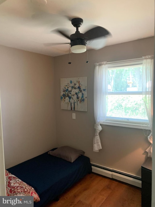 bedroom with hardwood / wood-style flooring, baseboard heating, and ceiling fan