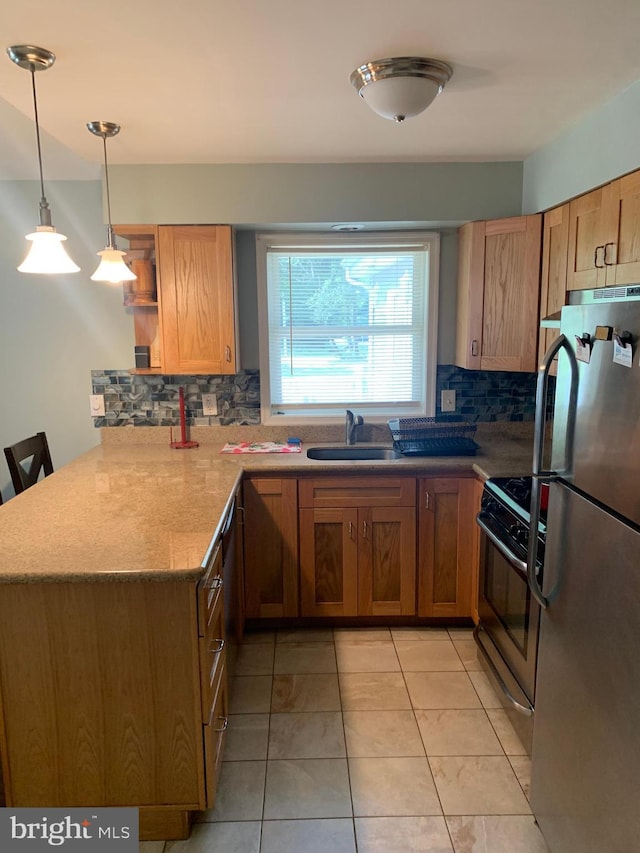 kitchen with kitchen peninsula, stainless steel fridge, a kitchen bar, range with gas stovetop, and sink