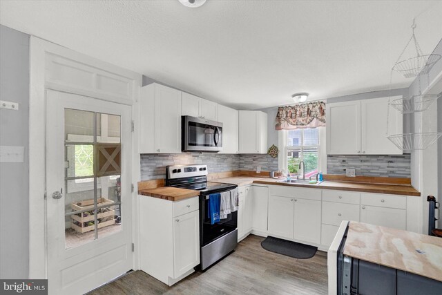 kitchen with sink, white cabinets, wooden counters, and appliances with stainless steel finishes