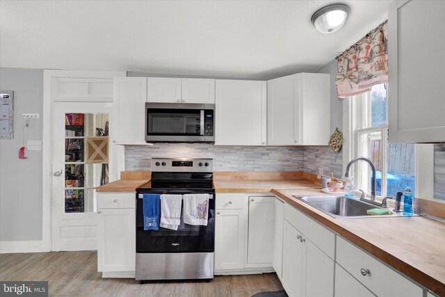 kitchen featuring white cabinets, wooden counters, stainless steel appliances, and tasteful backsplash