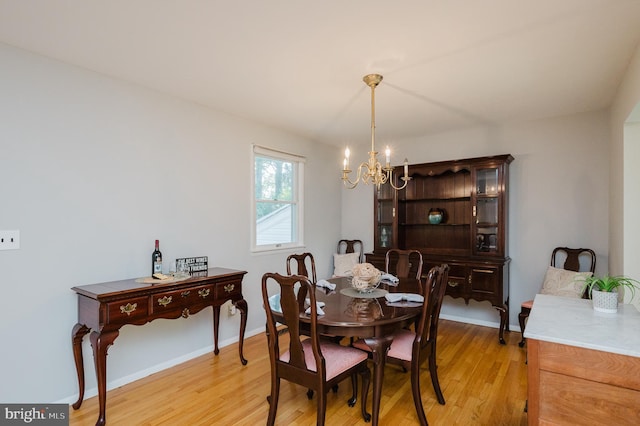 dining space with a chandelier, light wood finished floors, and baseboards