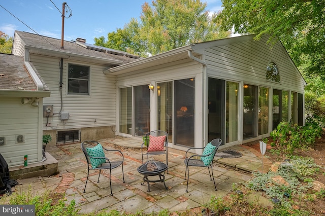 back of property featuring a patio area, an outdoor fire pit, and a sunroom