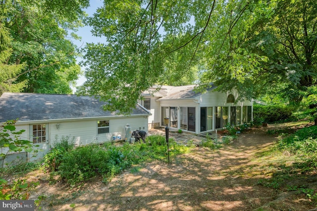 rear view of house featuring a sunroom and roof with shingles