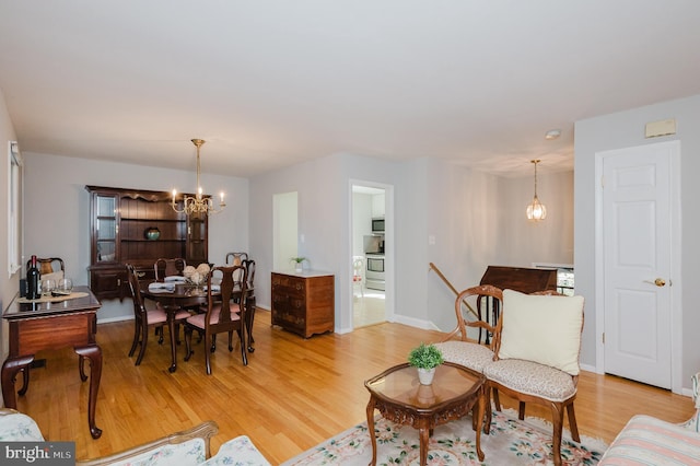 living room featuring a chandelier, light wood-style flooring, and baseboards