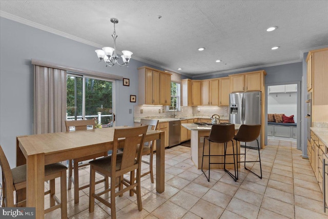 kitchen with an inviting chandelier, sink, hanging light fixtures, ornamental molding, and appliances with stainless steel finishes