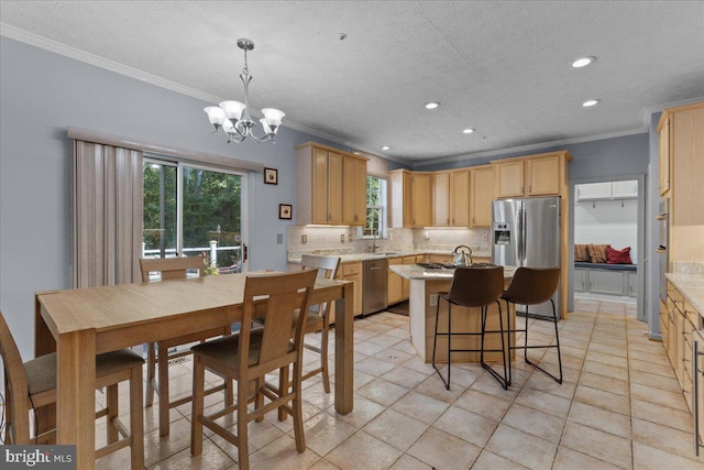 kitchen with sink, ornamental molding, appliances with stainless steel finishes, decorative light fixtures, and a chandelier