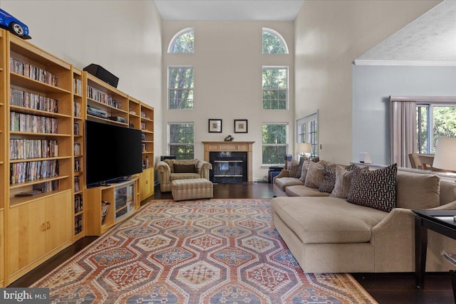 living room with crown molding, dark hardwood / wood-style flooring, and a towering ceiling