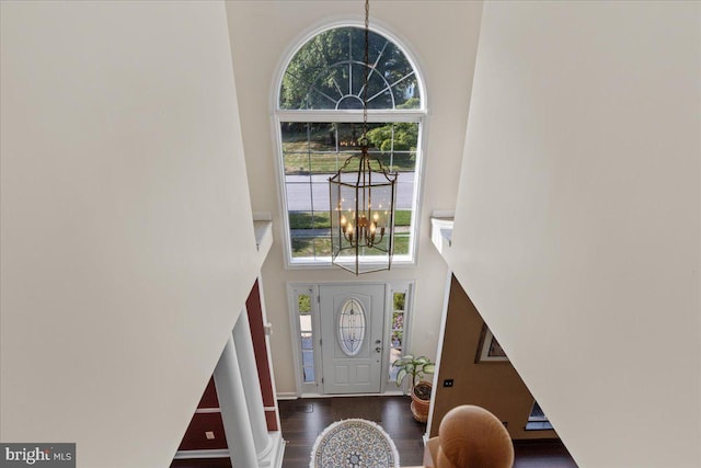 foyer entrance featuring a high ceiling, dark hardwood / wood-style floors, and an inviting chandelier