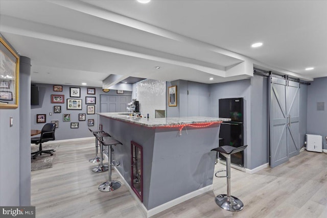 bar featuring light hardwood / wood-style floors and a barn door