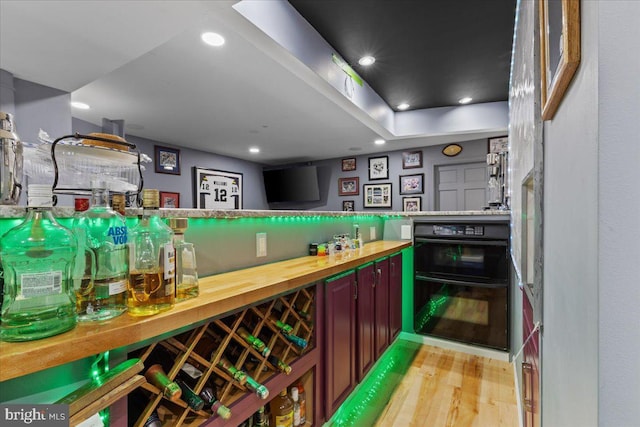 bar featuring light hardwood / wood-style floors and double oven