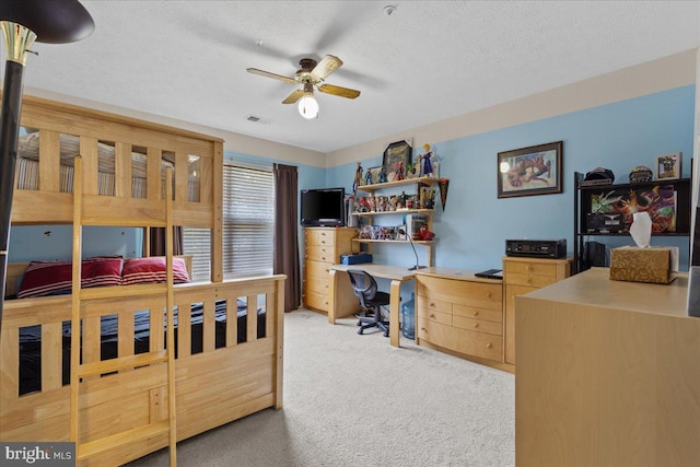 bedroom with ceiling fan, light colored carpet, and a textured ceiling