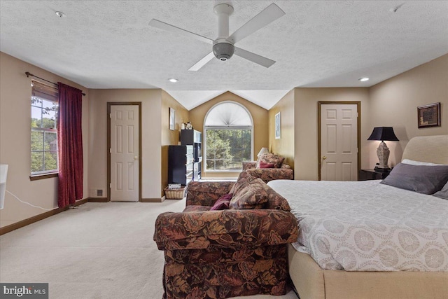 carpeted bedroom with a textured ceiling, vaulted ceiling, and ceiling fan