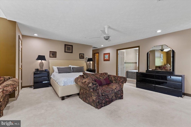 bedroom featuring ceiling fan, light colored carpet, ensuite bathroom, and a textured ceiling