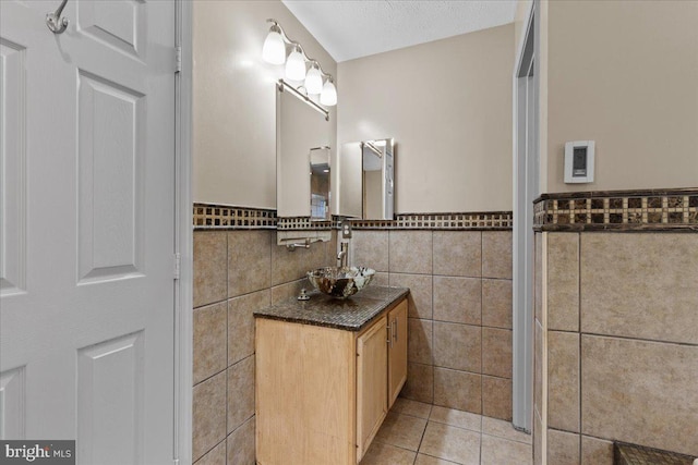 bathroom featuring tile patterned floors, a textured ceiling, vanity, and tile walls