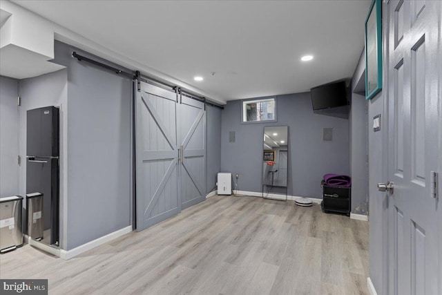 interior space with light wood-type flooring, a barn door, and refrigerator