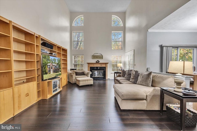 living room featuring dark wood-type flooring, a high ceiling, a high end fireplace, crown molding, and a textured ceiling