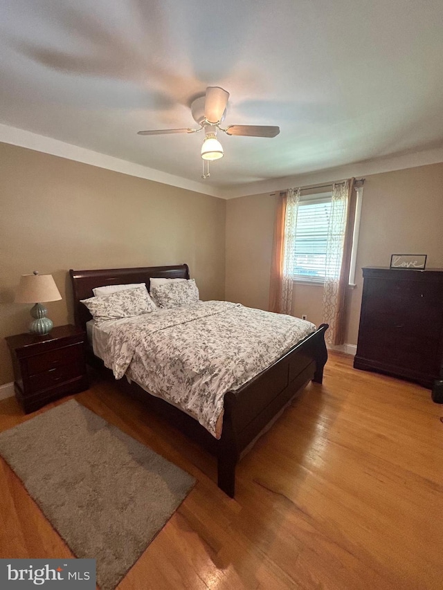 bedroom with wood-type flooring, crown molding, and ceiling fan