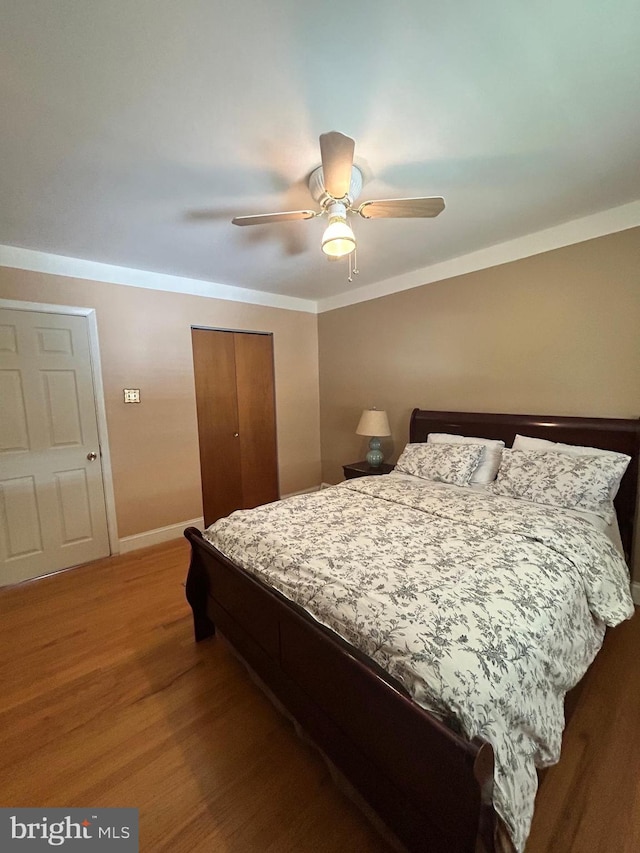 bedroom with ceiling fan, crown molding, hardwood / wood-style flooring, and a closet