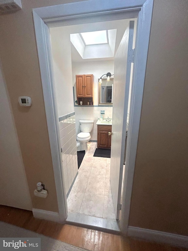 bathroom with a skylight, toilet, vanity, decorative backsplash, and wood-type flooring