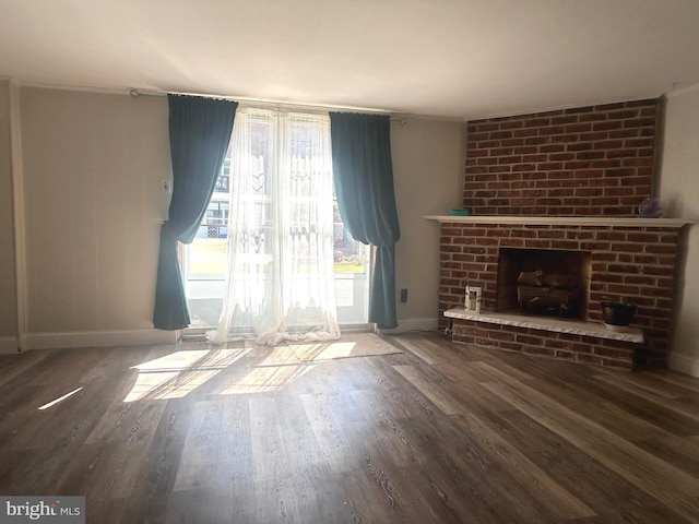 unfurnished living room with brick wall, dark hardwood / wood-style flooring, and a brick fireplace