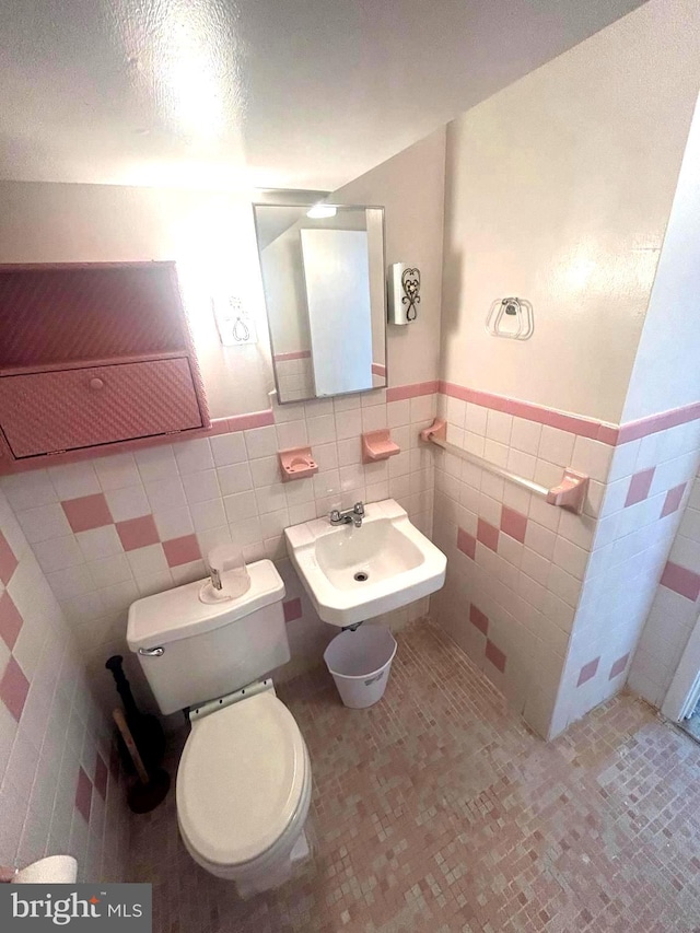 bathroom with tile patterned flooring, toilet, tile walls, decorative backsplash, and sink