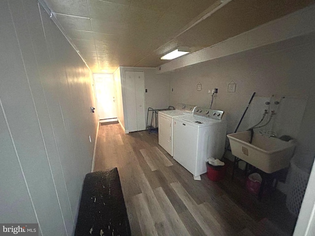 washroom with washing machine and clothes dryer, sink, and hardwood / wood-style floors