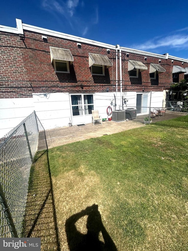 rear view of property featuring cooling unit and a yard