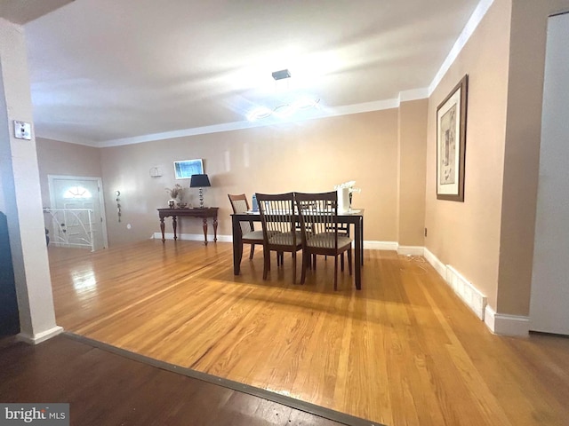 dining space with wood-type flooring and ornamental molding