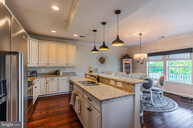 kitchen with light stone countertops, sink, stainless steel appliances, pendant lighting, and a center island with sink