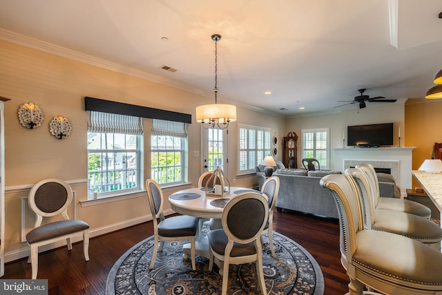 dining area featuring ornamental molding, ceiling fan with notable chandelier, and dark wood-type flooring