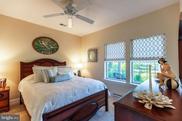 carpeted bedroom with ceiling fan and a baseboard heating unit