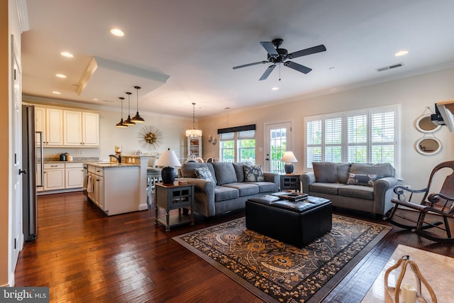 living room featuring ceiling fan with notable chandelier, dark hardwood / wood-style flooring, crown molding, and sink