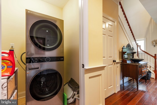 laundry room featuring dark wood-type flooring and stacked washer / drying machine