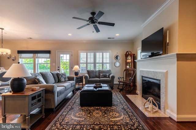 living room with ceiling fan, dark hardwood / wood-style flooring, a premium fireplace, and ornamental molding