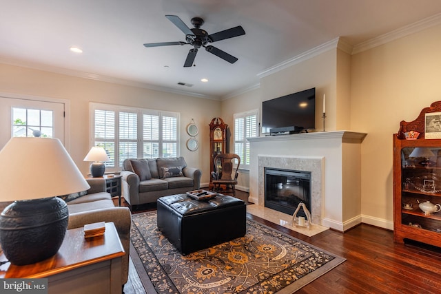 living room featuring a fireplace, crown molding, ceiling fan, and dark wood-type flooring