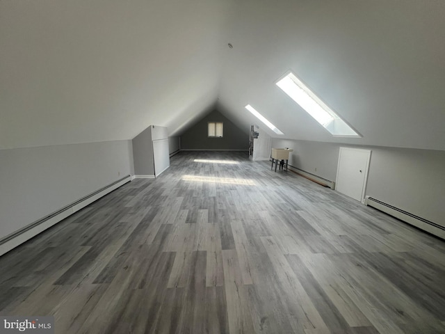 additional living space featuring wood-type flooring, a baseboard heating unit, and lofted ceiling with skylight