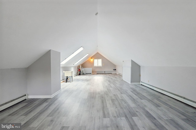 additional living space featuring vaulted ceiling with skylight, baseboard heating, and light wood-type flooring