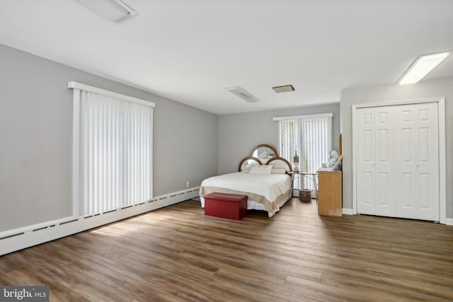 bedroom with a closet, dark hardwood / wood-style floors, and a baseboard radiator