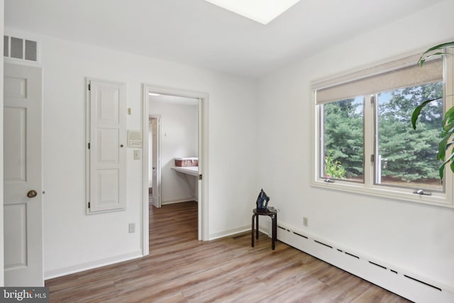 bedroom featuring light wood-type flooring and a baseboard radiator