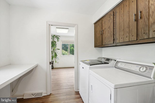 washroom featuring hardwood / wood-style flooring, cabinets, and independent washer and dryer